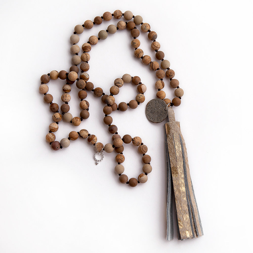 Matte picture jasper hand tied gemstone necklace paired with a gold leather tassel featuring a silver spirit medal