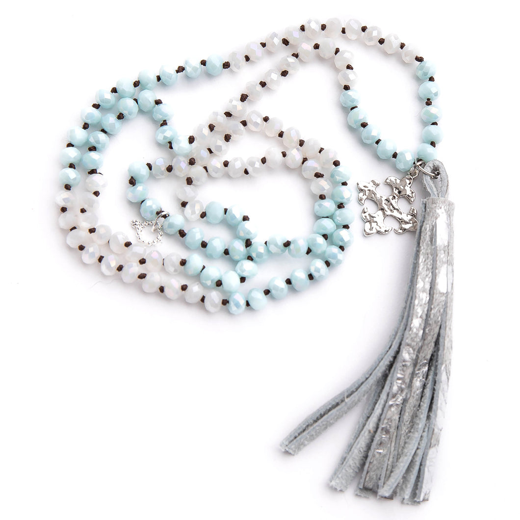 Hand tied faceted two tone aqua and white quartz gemstone necklace paired with a silver speckled leather print tassel featuring  a silver fleur cross