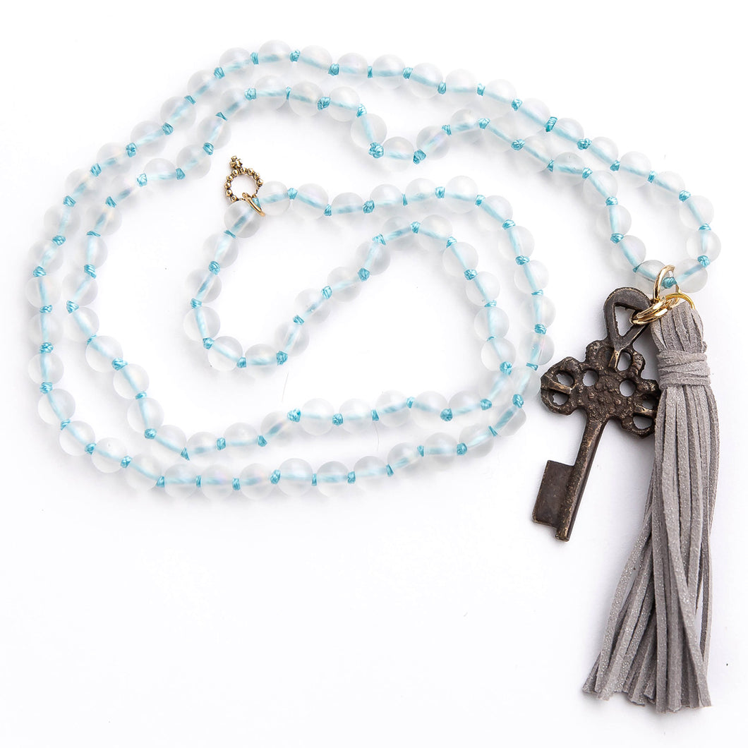 Hand tied frosted quartz gemstone necklace paired with grey leather tassel featuring a dark bronze rustic cross
