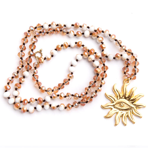Hand tied faceted gold and white quartz gemstone necklace paired with a large brass third eye sun