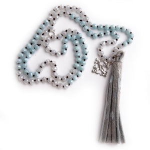 Hand tied faceted two tone aqua and white quartz gemstone necklace paired with a silver speckled leather print tassel featuring a silver fleur cross