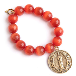 Firestone calcite paired with a large brass Queen of Heaven medal