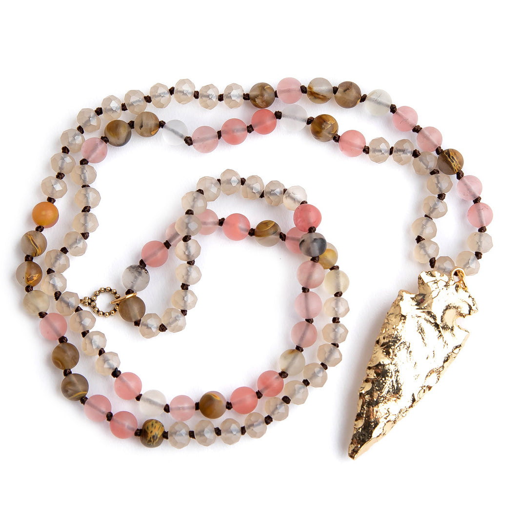 Hand tied matte cherry quartz gemstone necklace paired with a brass arrowheard